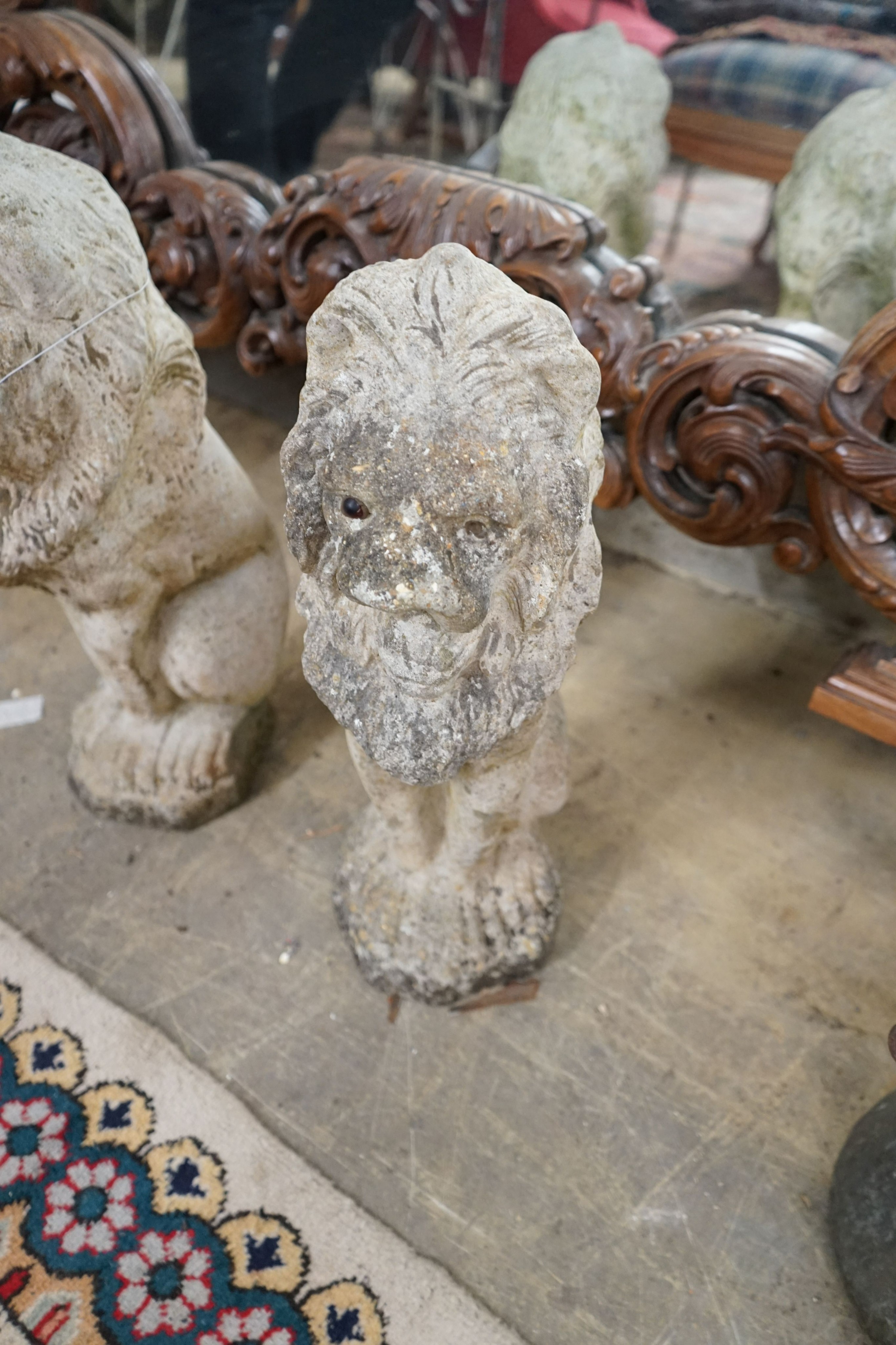 A pair of reconstituted stone seated lion garden ornaments, height 50cm